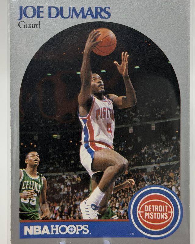 Joe Dumars Detroit Pistons NBA Hoops card showing a layup against a Celtics defender, in a plastic sleeve